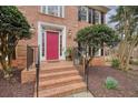Inviting entrance with a striking pink front door, brick steps, black railing, and manicured landscaping at 465 Woodbrook Ways, Lawrenceville, GA 30043