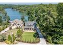 This aerial view showcases a well-manicured lawn near a lake, surrounded by lush greenery at 3441 Shoreland Dr, Buford, GA 30518
