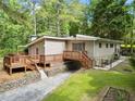 Lovely rear view with an expansive deck, complemented by lush greenery and mature trees at 609 Redwood Drive Dr, Woodstock, GA 30189