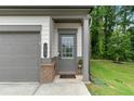 Close up of a gray door with glass panes, brick trim and the house number 153 at 153 Witter Way, Woodstock, GA 30188