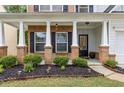 Inviting front porch with brick and white pillars, complemented by manicured landscaping and charming details at 4266 Suwanee Brook Ct, Buford, GA 30518