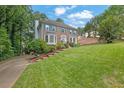 Charming two-story brick home featuring a well-manicured lawn, mature trees, and colorful flower beds at 3897 Tanbark Ct, Marietta, GA 30066