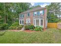 Charming two-story brick home featuring a well-manicured lawn, mature trees, and colorful flower beds at 3897 Tanbark Ct, Marietta, GA 30066