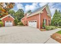 Side view of a brick home showcasing the attached and detached garages plus manicured landscaping at 4119 Alayna Lee Cir, Mcdonough, GA 30252