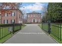 Stately brick home with black wrought iron fence and paved driveway leading to the front entrance at 4084 Peachtree Dunwoody Rd, Atlanta, GA 30342