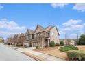 View of the two-story home on a landscaped lot, with a two-car garage, and manicured bushes in the front yard at 5621 Cobblestone Creek Ave # 14, Mableton, GA 30126