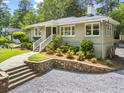 Brick home with manicured landscaping, stone retaining wall, gravel driveway, and inviting walkway at 2180 Howell Mill Nw Rd, Atlanta, GA 30318