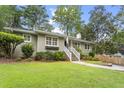 Charming single-story house featuring a lush front yard with stone pathway, flower beds, and mature trees at 2180 Howell Mill Nw Rd, Atlanta, GA 30318