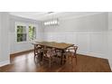 Formal dining room featuring wainscoting, hardwood floors, and a modern chandelier, perfect for entertaining at 2445 Kings Point Dr, Dunwoody, GA 30338