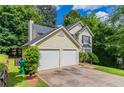 Two-car garage with driveway and well-maintained exterior surrounded by lush greenery and mature trees at 3732 Landgraf Cv, Decatur, GA 30034
