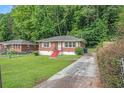 Quaint brick home with a front lawn, driveway and vibrant red stairs, surrounded by lush greenery at 2329 Polar Rock Sw Ave, Atlanta, GA 30315