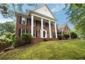 Elegant brick home with classic architectural details, featuring a landscaped yard and mature trees at 1595 Bakers Glen Dr, Atlanta, GA 30350