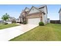 A side view of a brick and gray home with a long driveway leading to a two-car garage at 2537 Sori Dr, Buford, GA 30519