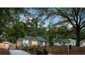 Charming home with a detached garage featuring string lights, nestled among mature trees and lush landscaping at 1583 Braeburn Se Dr, Atlanta, GA 30316