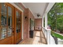Inviting front porch with wooden flooring, ceiling fan, and a cozy seating area, enhancing curb appeal at 5301 Regency Lake Ct, Sugar Hill, GA 30518