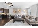 Bright living room featuring hardwood floors, ceiling fan, and dark kitchen cabinets at 2022 Talmai Dr, Snellville, GA 30078