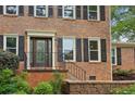 Close-up of front entrance with a detailed door, brick facade, and well-maintained landscaping at 9800 Woodfall Dr, Roswell, GA 30076