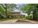 Beautiful two-story brick home with mature trees, a circular driveway, and manicured landscaping at 9800 Woodfall Dr, Roswell, GA 30076