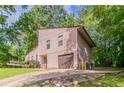Home featuring a garage and a private driveway, surrounded by lush greenery and mature trees at 3851 Natalie Way, Ellenwood, GA 30294