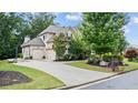 Side view of a brick home featuring an attached garage, long driveway, and manicured lawn at 1980 Marcia Overlook Dr, Cumming, GA 30041