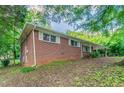 Brick home with white trim featuring a carport and a spacious yard with mature landscaping at 4078 Bouldercrest Rd, Ellenwood, GA 30294