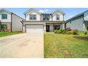 Charming two-story home featuring a two-car garage, lush green lawn, and inviting front entrance at 4720 Dufour Dr, Lilburn, GA 30047