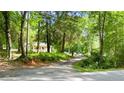 A gravel driveway leads up to a charming home, nestled among mature trees and lush greenery at 12728 Bells Ferry Rd, Canton, GA 30114