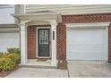 Inviting townhome entrance featuring brick facade, covered porch, black front door, and attached one car garage at 6895 Slate Stone Se Way # 3, Mableton, GA 30126