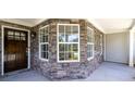 Covered porch with stone detailing and large windows providing ample natural light at 895 Roxfield Ct, Buford, GA 30518