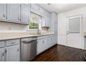 Kitchen features stainless steel dishwasher, gray cabinets, window, and exterior door with blinds at 1828 Brandy Woods Se Dr, Conyers, GA 30013