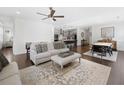 Open-concept living space with hardwood floors, ceiling fan, and abundant natural light flowing into the modern kitchen at 209 Floral Valley Dr, Woodstock, GA 30188