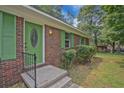 Close-up of a brick home featuring a green front door and shutters adding character and curb appeal at 622 Sheffield Rd, Norcross, GA 30071