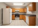 Functional kitchen with oak cabinetry, white appliances, and tile flooring at 7070 Ravenwood Ln, Lithonia, GA 30038