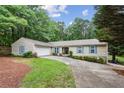 Traditional home exterior with a two-car garage, blue shutters, a well-maintained lawn, and mature trees in the background at 1185 Wedgefield Sw Dr, Marietta, GA 30064