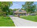 Inviting blue home featuring a covered front porch and driveway in a lush green yard at 1382 6Th Ave, Auburn, GA 30011