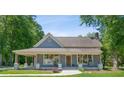 Charming blue home with a covered front porch surrounded by lush green trees and a well-manicured lawn at 1382 6Th Ave, Auburn, GA 30011