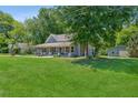 Quaint blue house with covered porch, surrounded by large trees and a big lawn at 1382 6Th Ave, Auburn, GA 30011