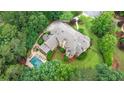 Aerial view of an estate featuring a large brick home, in-ground pool with spa, well-maintained landscaping, and mature trees at 816 Blackfoot Trl, Suwanee, GA 30024