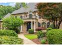 Elegant brick home featuring a charming front porch, balcony, and meticulously maintained landscaping at 816 Blackfoot Trl, Suwanee, GA 30024