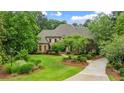Expansive green lawn and a circular driveway leading to a stately brick home surrounded by lush landscaping and mature trees at 816 Blackfoot Trl, Suwanee, GA 30024