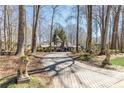 Paver driveway approach to a charming Tudor-style home with mature trees and lion statues at 4210 Gatewood Ln, Peachtree Corners, GA 30097