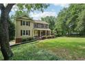 Inviting two-story home with a covered front porch, landscaped yard, and mature trees creating a serene setting at 10875 Shagbark Trl, Roswell, GA 30075
