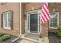Charming brick home featuring a black front door flanked by potted plants and an American flag at 1245 Mountain Ivey Ct, Sugar Hill, GA 30518