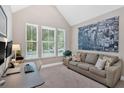 Cozy living room featuring a comfortable gray sofa, three windows, neutral carpet, and a stylish wall art piece at 12 Pine St, Roswell, GA 30075