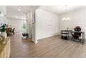 Open-concept living room with light wood floors, neutral walls, chandelier lighting, and view into kitchen and entryway at 228 Whitneys Way, Dallas, GA 30157