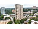 This aerial view showcases the building in relation to the shops and parking area with city views in the distance at 2881 Peachtree Ne Rd # 1202, Atlanta, GA 30305