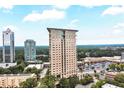 Aerial view of a high-rise building with a cityscape in the background, trees, and a parking lot area nearby at 2881 Peachtree Ne Rd # 1202, Atlanta, GA 30305