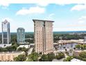 Aerial view of a tall, modern apartment building with tree top views, a parking area, and shopping close by at 2881 Peachtree Ne Rd # 1202, Atlanta, GA 30305