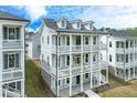 View of three story home featuring double balconies, white trim and dormer windows at 1294 Six Sisters St, Dacula, GA 30019