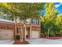 Two-story townhome with a brick facade, attached garage, and small front porch at 2735 Sudbury Trce, Norcross, GA 30071